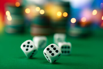 White dice on a green felt table with bokeh background