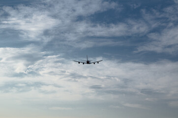 Fototapeta na wymiar Silhouette of an airplane flying isolated on cloudy sky day background.