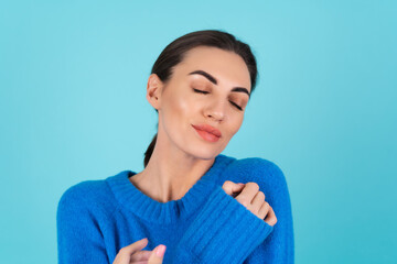 Young woman in a blue knitted sweater and natural daytime makeup on a turquoise background, plump...