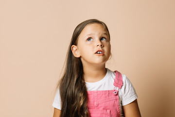 Portrait of child with shining bright eyes looking upward and eyebrows raised, with pensive,...