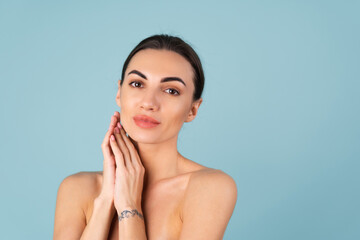 Close beauty portrait of a topless woman with perfect skin and natural make-up, plump nude lips, on a blue background