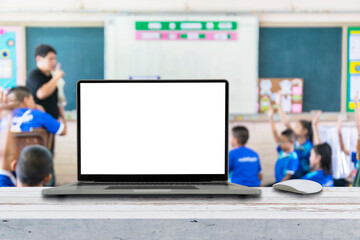 Computer on the table, blur image of children in the classroom