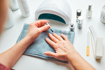 Woman applying gel hybrid polish using UV lamp. Beauty wellness spa treatment concept. Cosmetic...