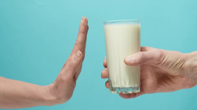 Lactose intolerance. Glass of milk and hand showing stop.