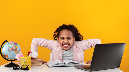 Furious african school girl looking at camera using laptop