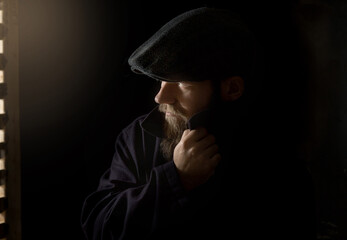 portrait of a bearded young man in a vintage cap close-up, looking into the camera. the collar of his coat is turned up.