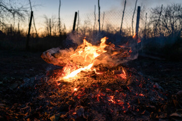 fire smolders on hot ash in garden in dusk