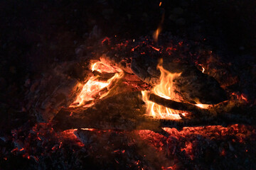 fire smolders between burned logs close up
