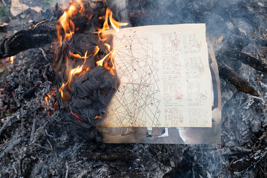 vintage dress cutting patterns buring in old bonfire in country garden at dusk