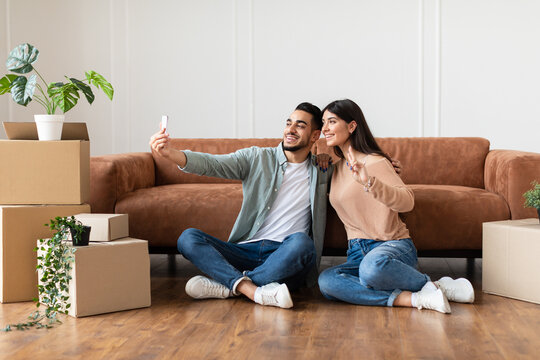 Happy man and woman taking selfie in their new apartment