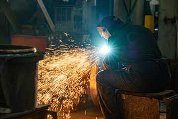 The welder cuts with a graphite carbon electrode. Sparks fly to the side.