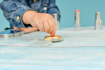 Girl child applies eye shadow powder on a brush.