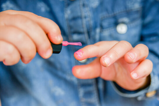 Nail polish in the hands of a child. Children clumsily use their parents' makeup.