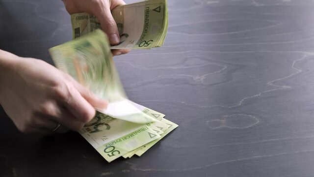4k. Close-up view of counting stack of belarusian 50 ruble paper money. Hands hold and count a lot of cash. Saving. National currency of Belarus. Credit liabilities. Profit. Big debt. Taxes payment.