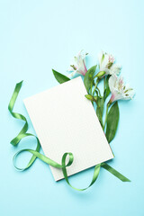 Lilies, green ribbon and space for text on blue background