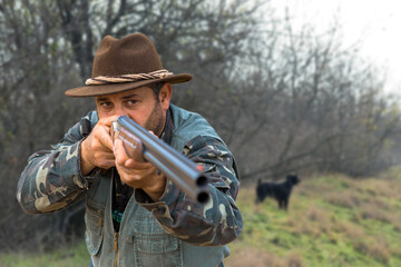 Hunter man in camouflage with a gun during the hunt in search of wild birds or game. Autumn hunting season.