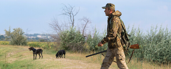 Hunter man in camouflage with a gun during the hunt in search of wild birds or game. Autumn hunting season.