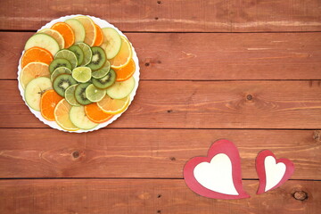 beautifully arranged Fresh orange slices. green kiwi. Lemon. Pear. lime on a white plate. on a wood background. holiday concept. love for happy women, mom, Valentine's Day