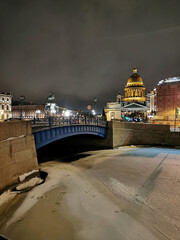 View of the Blue Bridge over the Moika River, St. Isaac's Cathedral and trees decorated with garlands for Christmas and New Year.