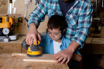 Father carpenter and son boy work in the workshop. Master dad teaches his son carpentry. Continuity...