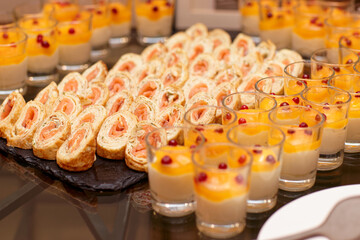 Pancakes rolls with salmon and glasses of panna cotta