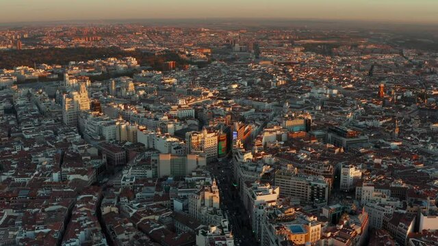 Aerial panoramic view of large city at sunset. Gran Via street in city centre surrounded with tall buildings.