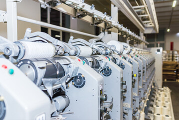 Cotton Yarn Production in a Textile Factory. Textile fabric manufacturing machines in work. Row of...