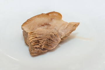 Boiled ham pork thigh on a plate on a white background. Close up. Selective focusing.