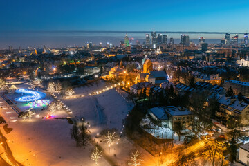 Fototapeta na wymiar Warszawa, multimedialny park fontann ozdobiony świątecznymi lampkami, odległe centrum miasta, zimowy krajobraz z lotu ptaka
