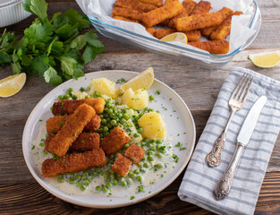 Fish sticks with green peas and potatoes in a bechamel sauce on a plate