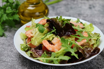 Fresh and healthy vegetable salad made of tomato, rucula, lettuce, shrimps and spices. Healthy food concept.