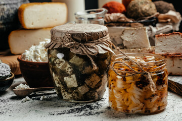 glass jar with cheese in olive oil and aromatic herbs on a dark background. banner, menu, recipe...