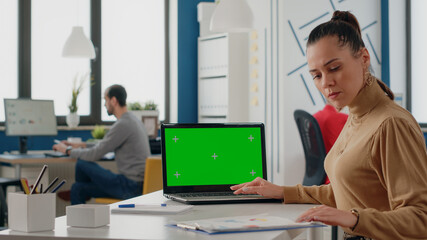 Person working with green screen on laptop in business office. Woman employee using computer with...