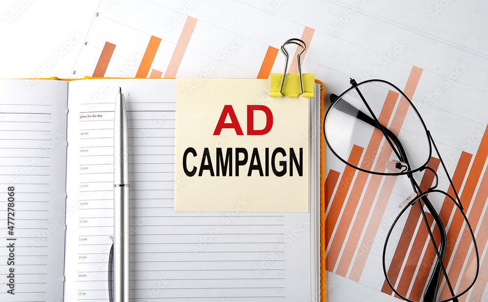 Poster ad campaign text on a notepad with laptop on the white background