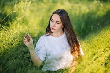 Portrait of a young girl in the green grass on a summer day.