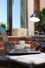 Startup owner hand touching laptop trackpad browsing internet sitting at desk in new business...