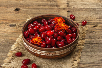 Ripe dogwood berry with bright marigold flowers on old wooden table