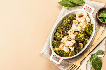 Baked broccoli and cauliflower on light beige background