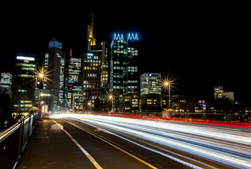 Fototapeta na wymiar Traffic light rays on a street on a bridge in Frankfurt - Main at night with view to the skyline of the city at a cold day in winter.