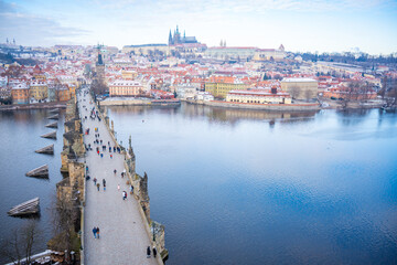 Fototapeta premium People are walking on Charles bridge, whose rooftops are covered by snow, Prague in the winter