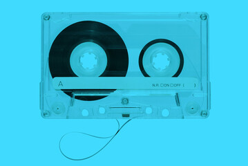 Retro music cassette with tape on cyan background