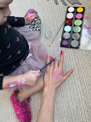 Little girl drawing nails for mama. Pink paint