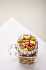 Glass jar filled with a variety of nutrition and healthy snacks and nuts on a white background