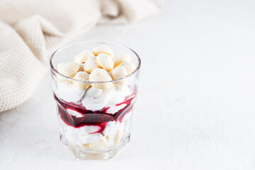 Sweet dessert with aquafaba meringue, coconut cream and cherry in a glass on the table. Sugar, lactose free, vegan. Horizontal orientation, copy space.