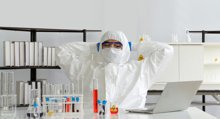 Epidemiological researcher in virus protective clothing sit back and relax after receiving emails of their latest research. Coronavirus disease 2019 (COVID-19) testing process in a laboratory.