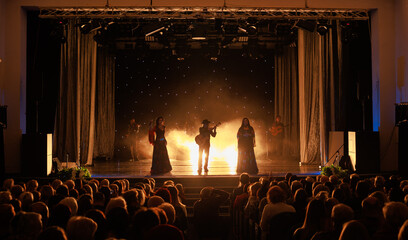 A collective of musicians, singers and dancers in gypsy costumes perform on stage.