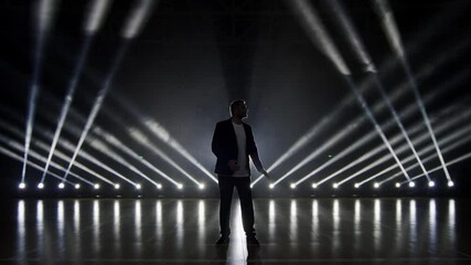 Famous Showman, artist in black suit performs on stage 4K. The silhouette of a singer in the dark with bright spotlight. - Powered by Adobe