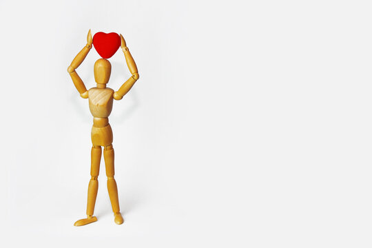 yellow wooden mannequin holding a red heart