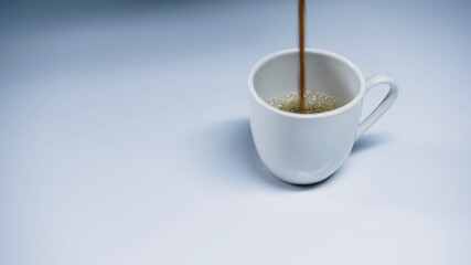hot espresso pouring into cup on white.