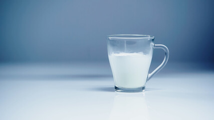 glass of fresh milk on white and grey.